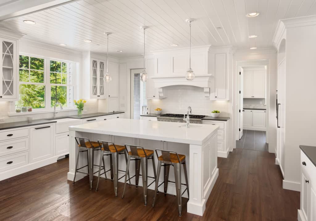 Beautiful white kitchen in new luxury home with island, pendant lights